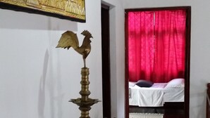 Ein Flur mit einer Messingskulptur, einem Bett mit roten Vorhängen und einem Gemälde an der Wand.