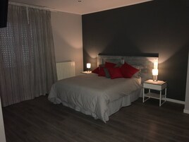 Una camera da letto con un letto, due comodini con lampade, una finestra con tende e una parete scura.