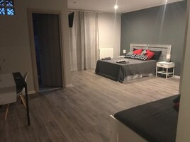 Una camera d'albergo con un letto, un comodino e una scrivania con una sedia.