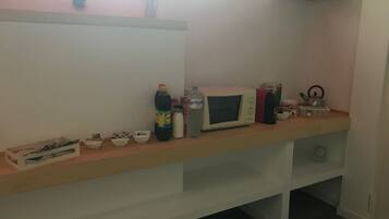 Una cucina con forno a microonde, bollitore e diversi utensili da cucina su un piano di lavoro in legno.