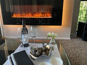 A table with a bottle of wine, two glasses, a vase with flowers, and chocolate-covered strawberries. - Amaré Beachside Luxury (Turners Beach)