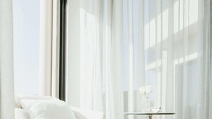 Una sala de estar moderna con un sofá blanco, un sillón redondo y una mesita con un florero.