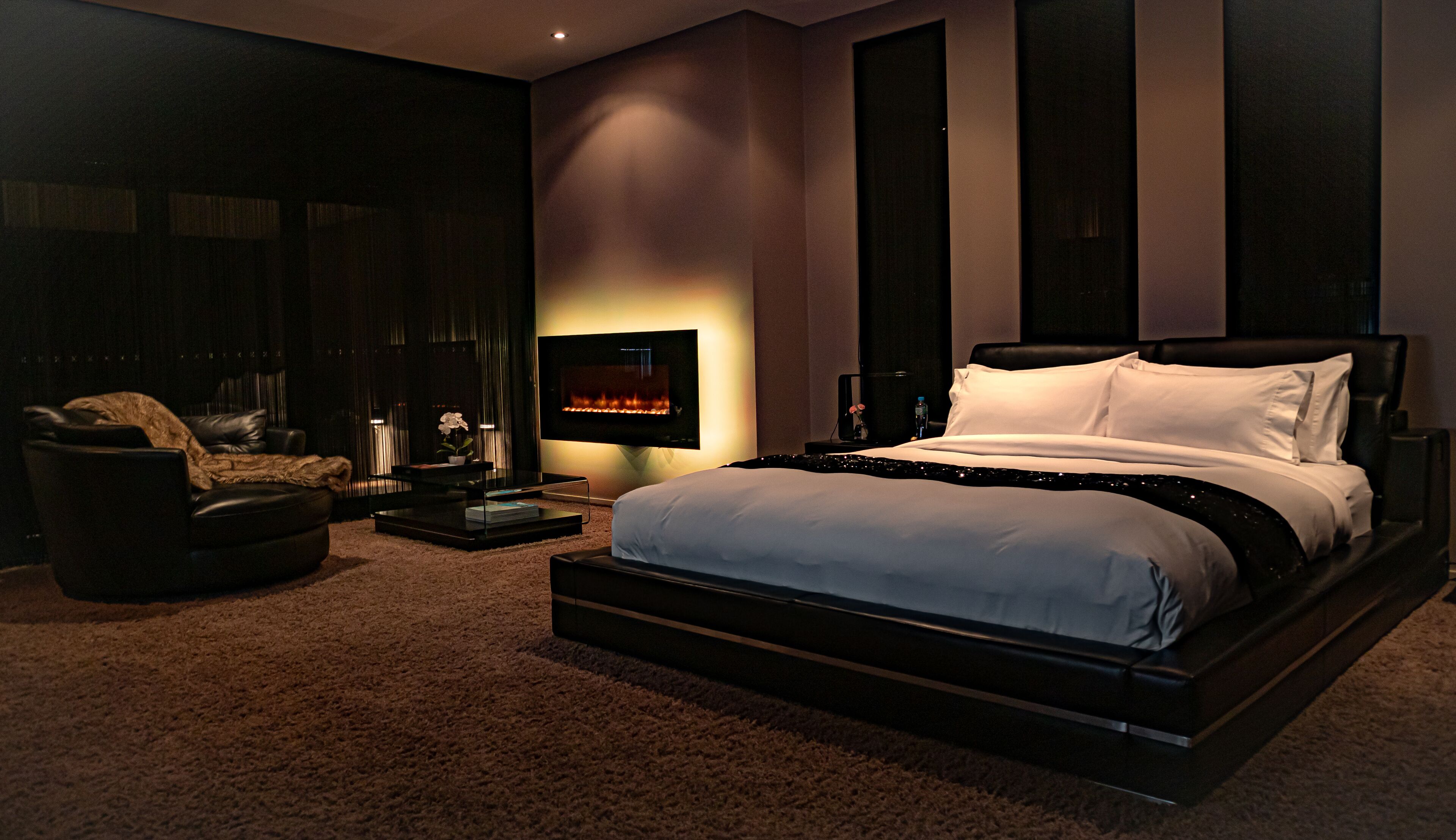 A modern bedroom with a large bed, a TV, and a seating area with a sofa and coffee table.