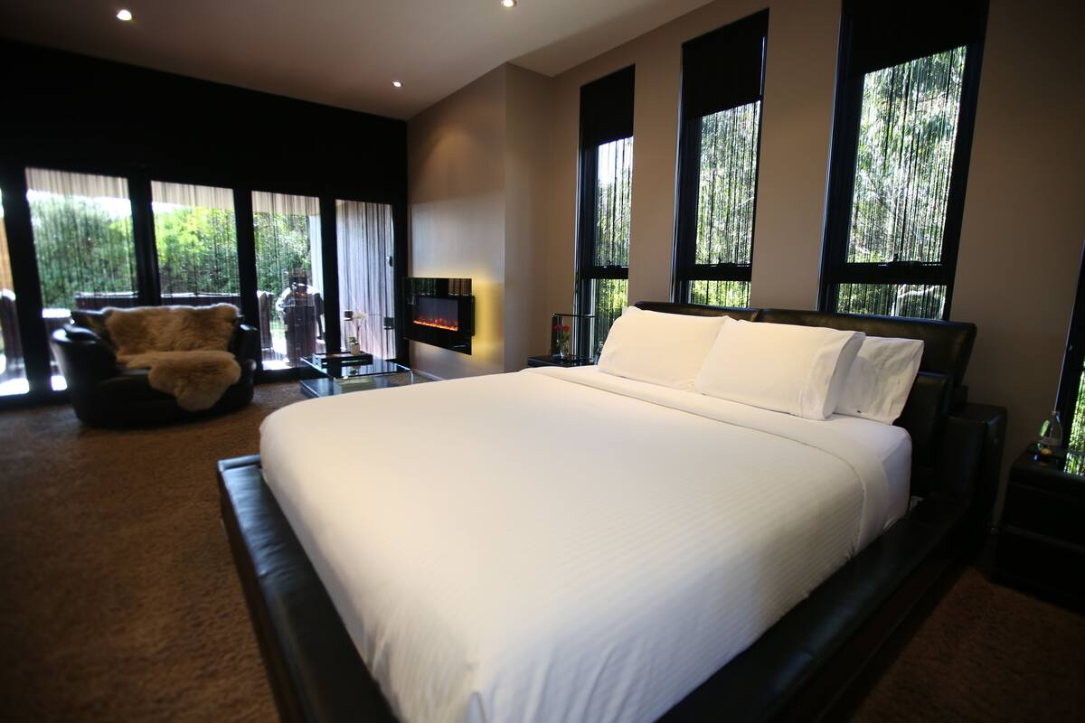 Um quarto espaçoso com uma cama grande, uma cadeira e uma televisão.