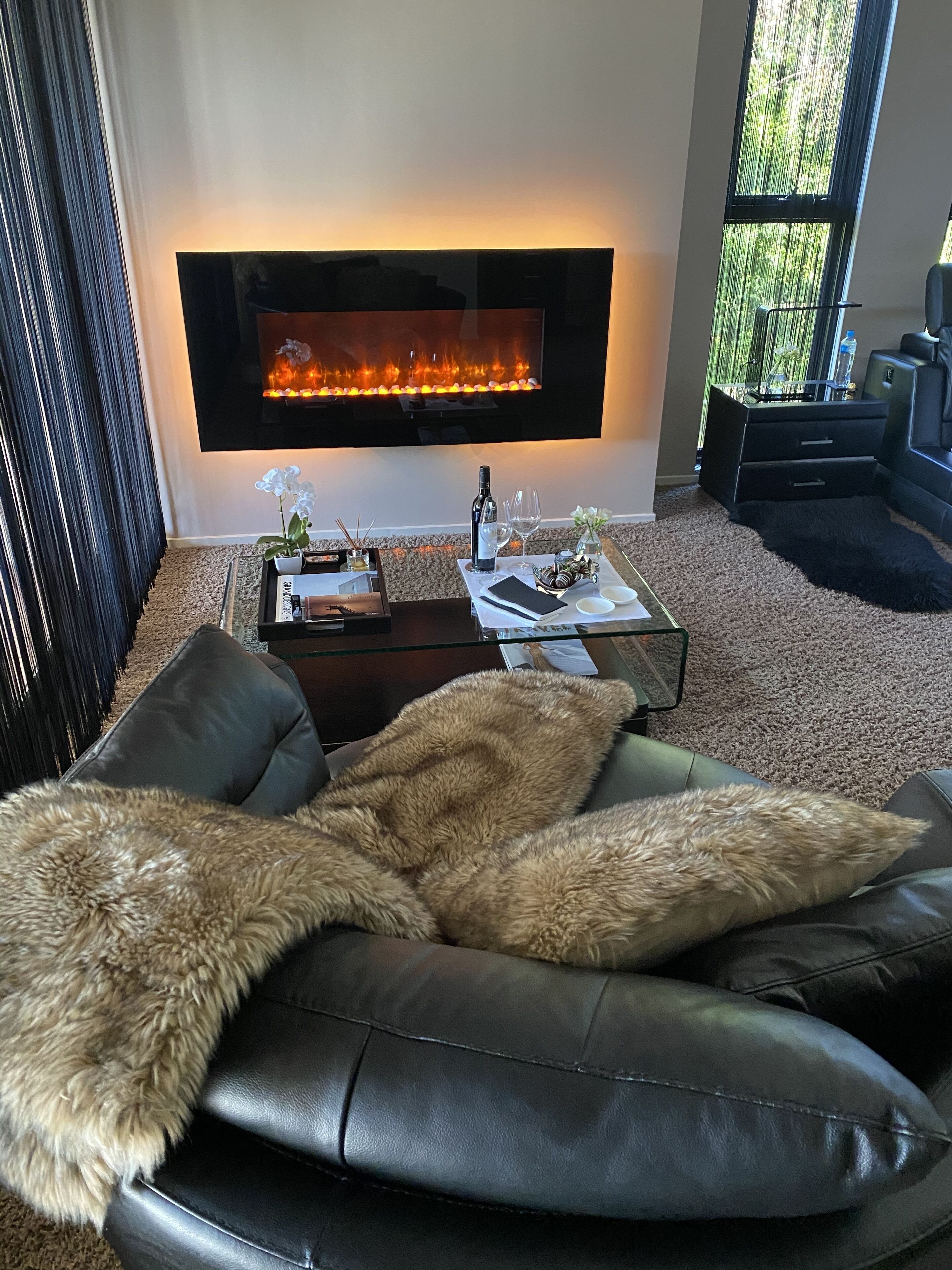 Una sala de estar moderna con un sofá de cuero, una mesa de centro de vidrio y una chimenea.