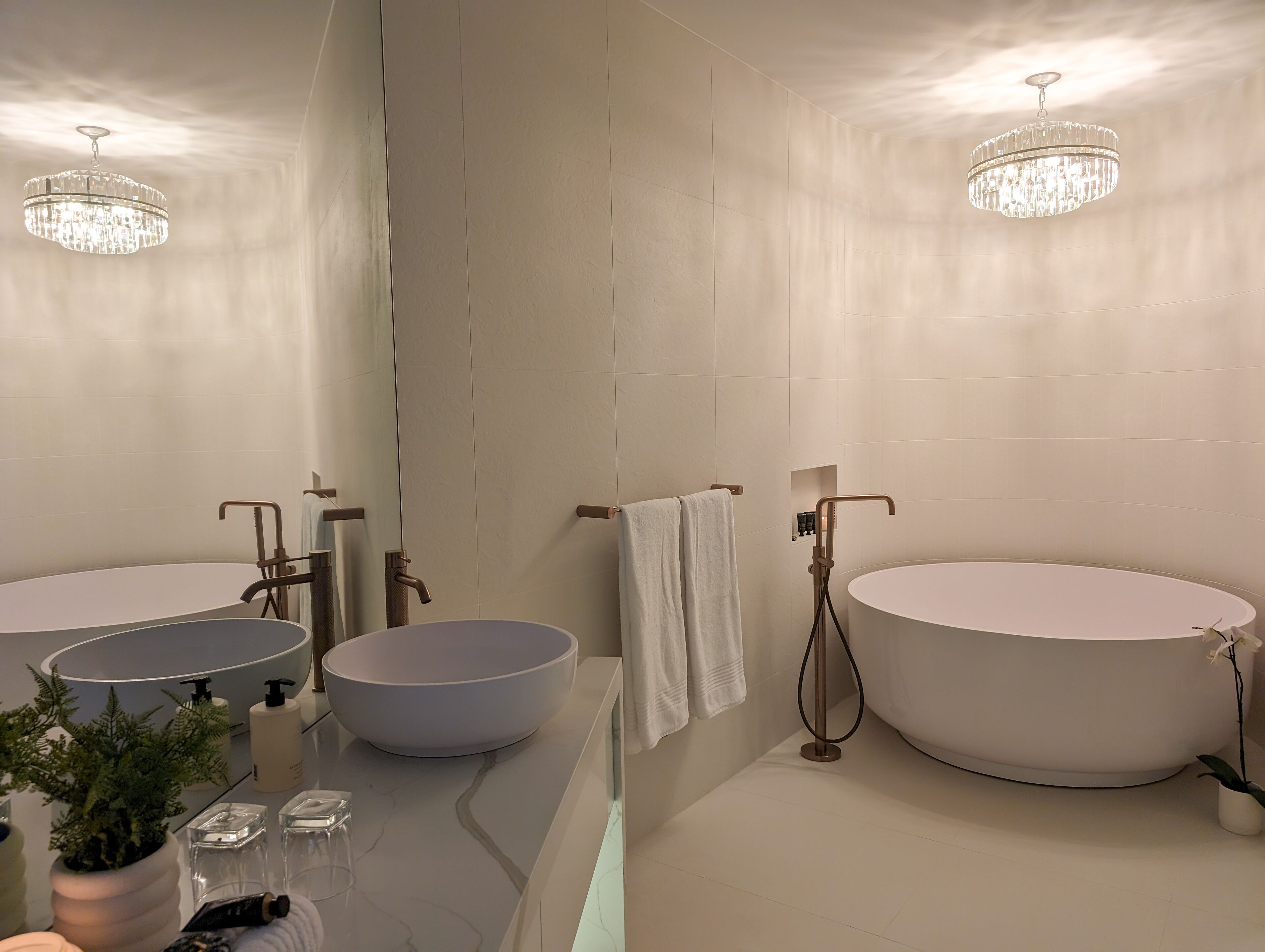A modern bathroom with a large bathtub, a round sink, and two mirrors.