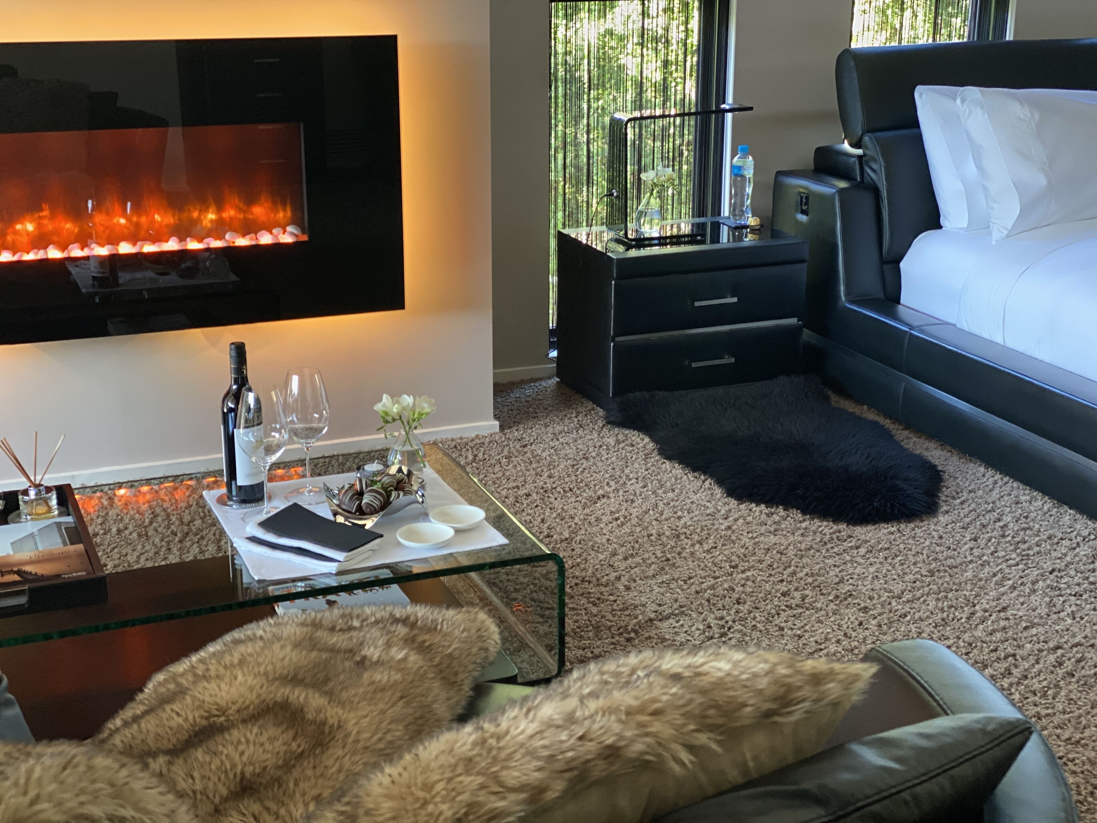 A modern bedroom with a flat-screen TV, a glass coffee table, a sofa, and a bed.