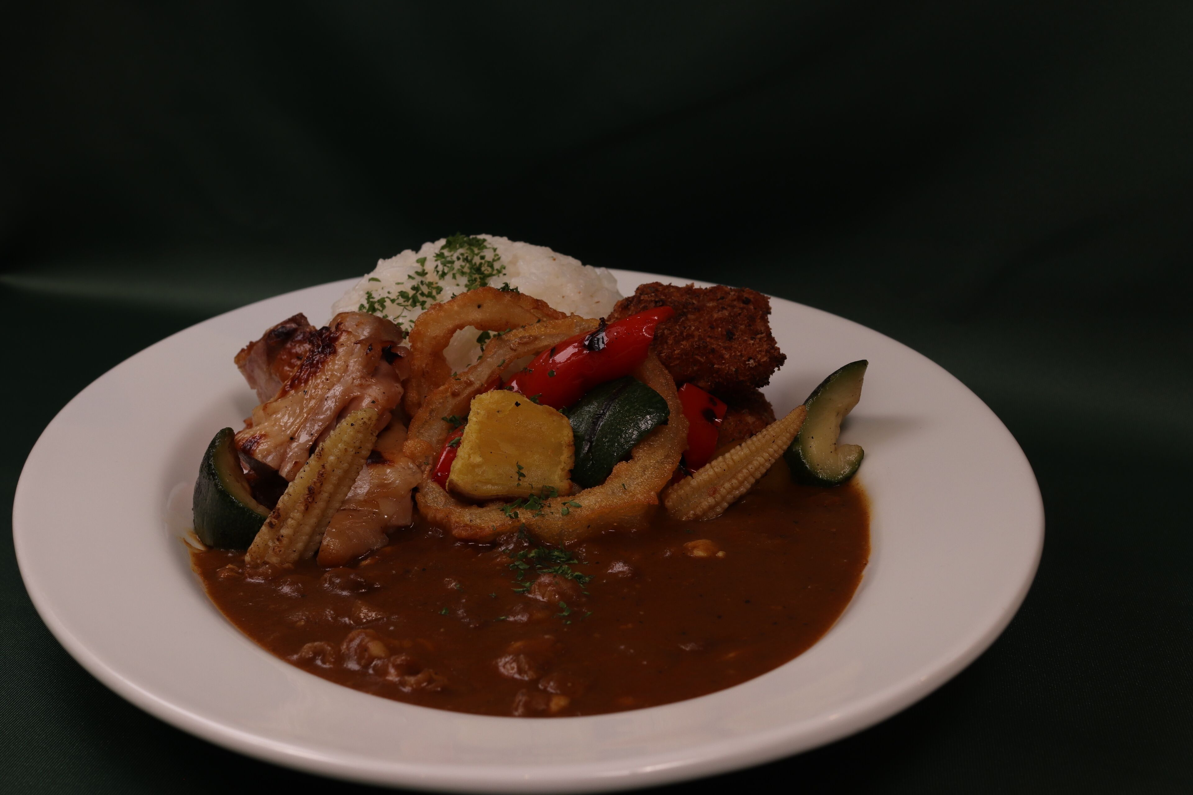 Un plato de comida con arroz, carne a la parrilla, verduras y salsa.