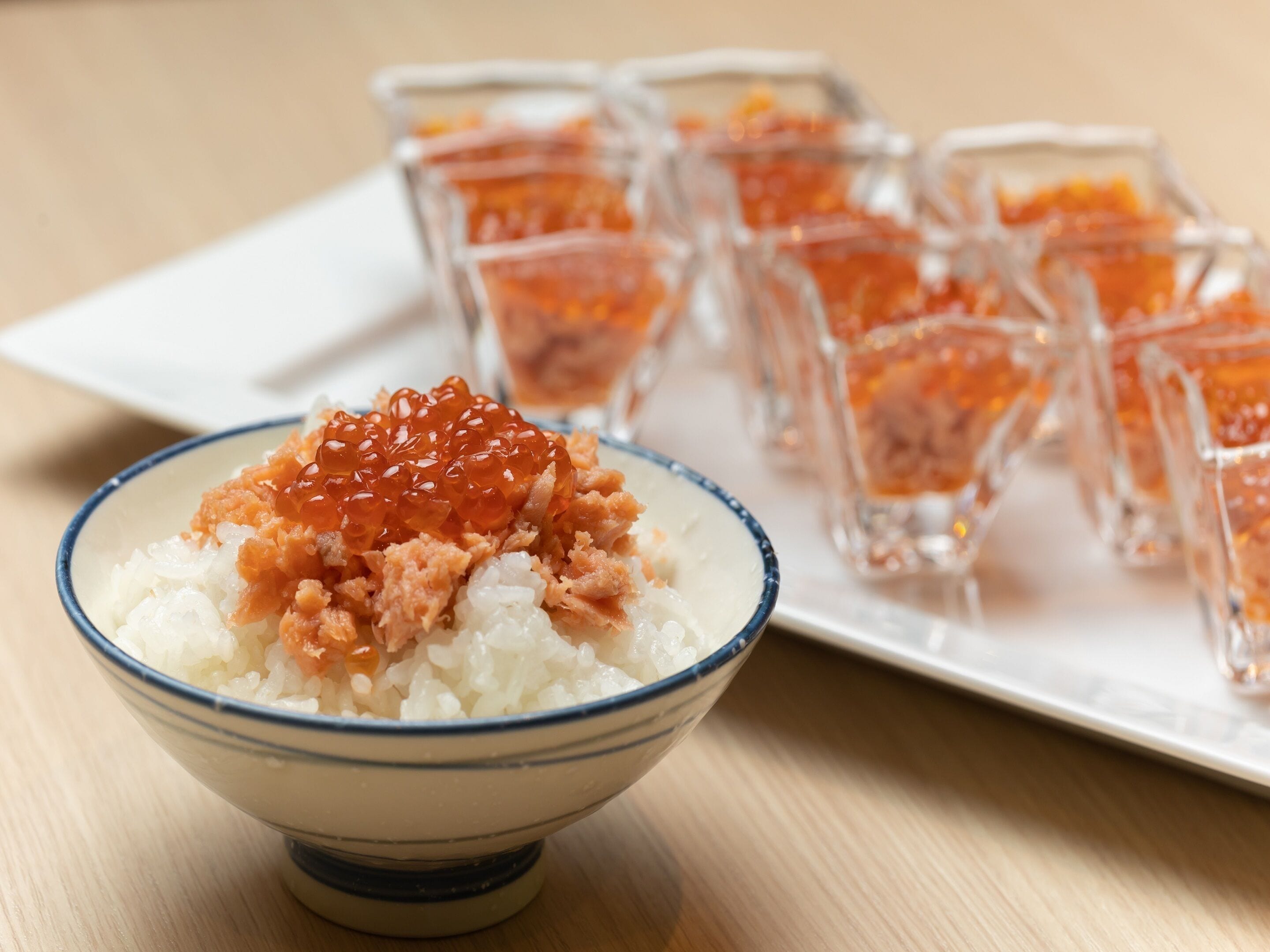 Un bol de riz garni de caviar de saumon et une assiette remplie de petits verres contenant du caviar de saumon.