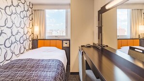 Una habitación de hotel con cama, escritorio, espejo y ventana con vistas a la ciudad.