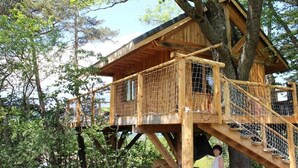 Ein hölzernes Baumhaus mit mehreren Ebenen und einer Holztreppe.