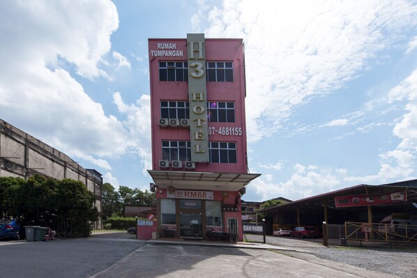 A pink hotel with a sign reading "Rumah Tumpangan" and a phone number. There is a car park in front. - Collection O Yong Peng Near Dataran Gemilang Formerly H3 Hotel (Batu Pahat)