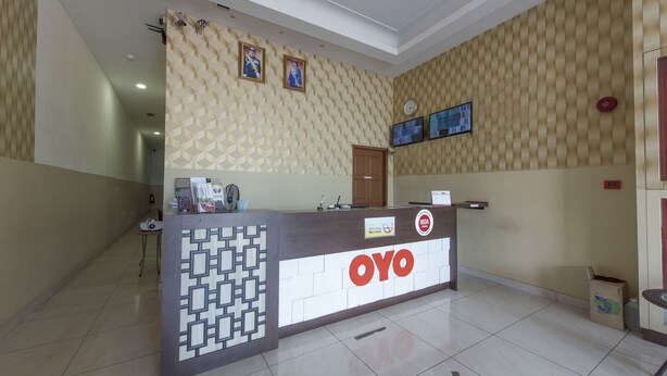 A reception area with a patterned wall, a reception desk, and a clock. - Collection O Yong Peng Near Dataran Gemilang Formerly H3 Hotel (Batu Pahat)