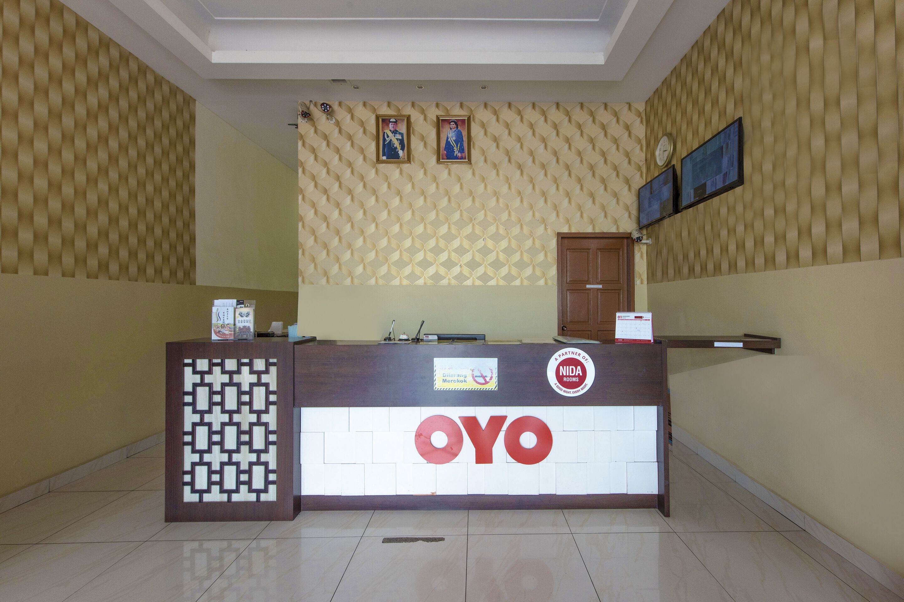 A reception desk with a patterned wall and a clock.