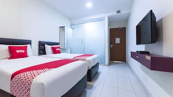 A hotel room with two beds, a TV, a wardrobe, and a door leading to a bathroom.