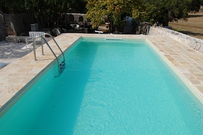 A rectangular swimming pool with clear blue water, surrounded by stone tiles and a stone wall. - Masseria Santanna (Monopoli)