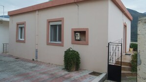 Un edificio de una planta con techo plano, un pequeño porche y una entrada con reja.