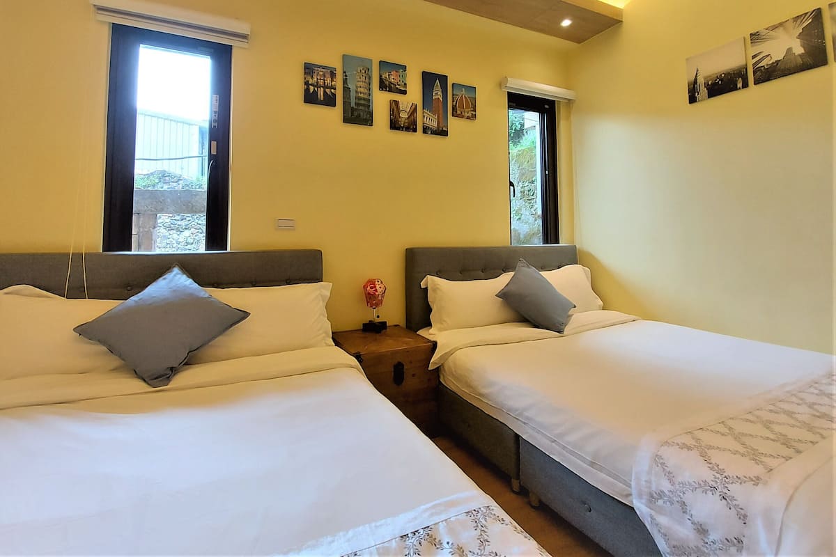 Habitación de hotel con dos camas, una mesita y una ventana.