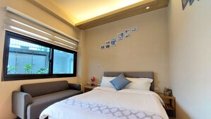 Un dormitorio moderno con una cama grande, un sofá, una ventana con persianas y una pared decorada con cuadros.