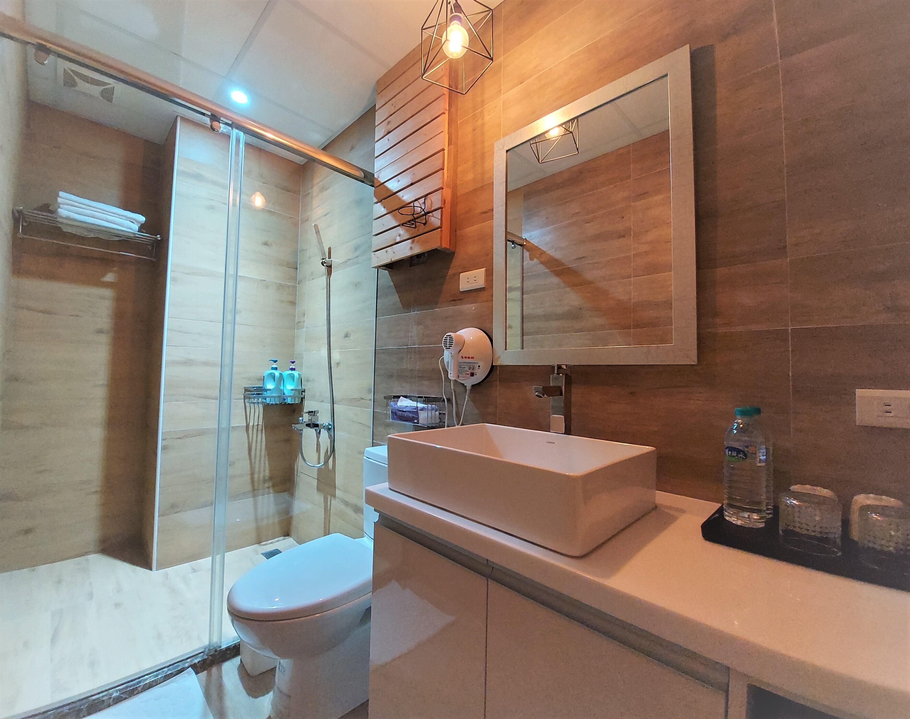 A modern bathroom with a glass-enclosed shower, a white sink, and a large mirror.