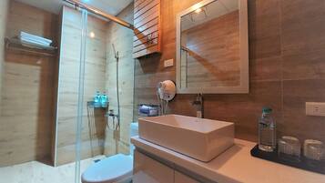 A modern bathroom with a glass-enclosed shower, a white sink, and a large mirror.