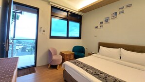 Habitación de hotel con cama, una silla, una mesita y ventana con vista a edificios.