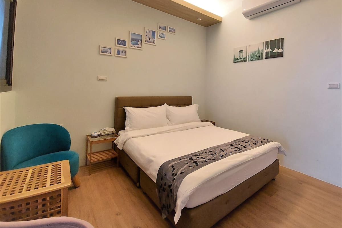 Un dormitorio con cama, una silla, una mesita de noche y adornos en la pared.