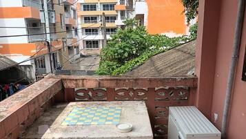 Un pequeño espacio al aire libre con una mesa y bancos, rodeado por un muro de ladrillo y una barandilla de metal.