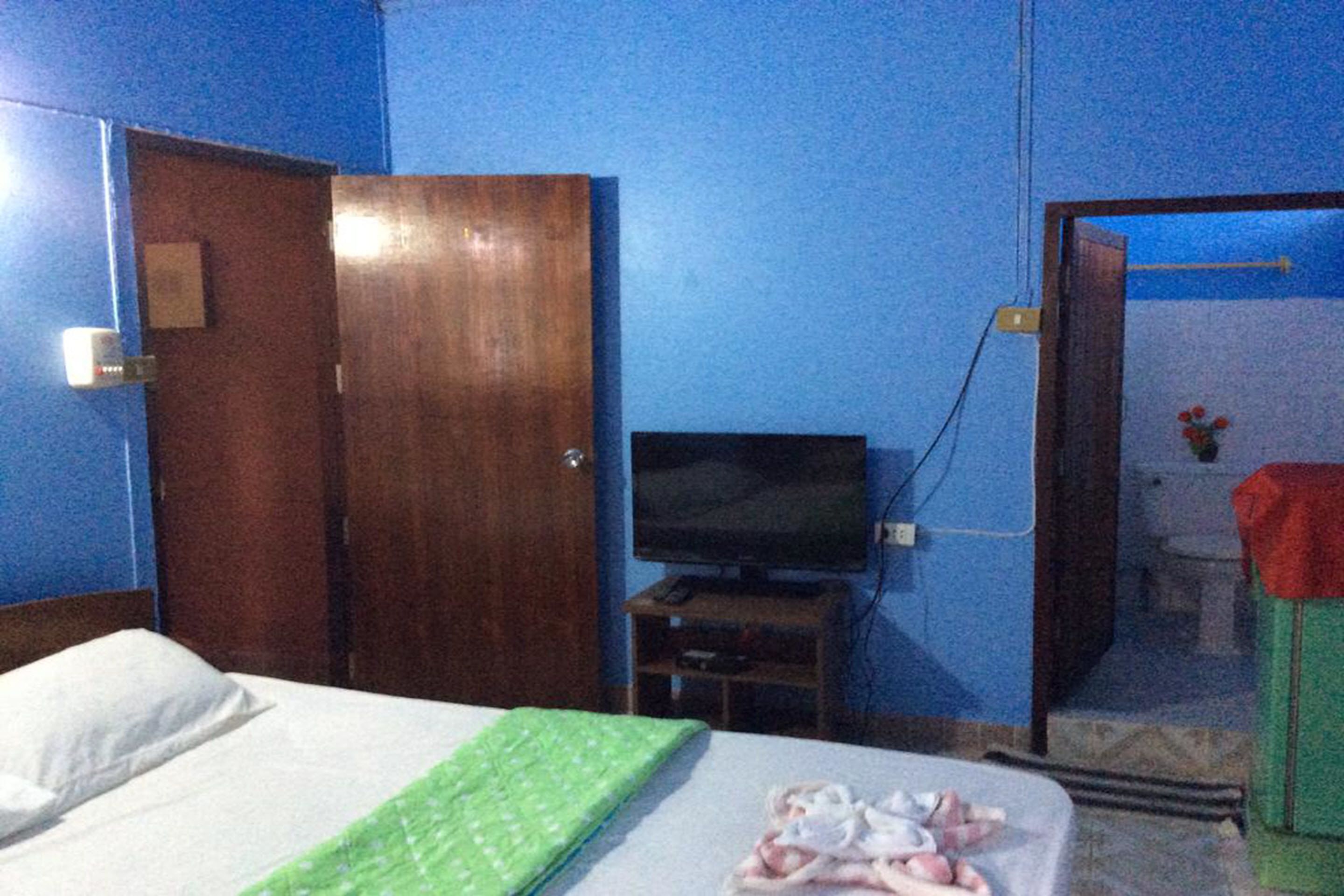 A room with a bed, a television, and a bathroom visible through an open door.