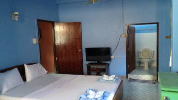 Una habitación con una cama, televisión, espejo y un armario verde.
