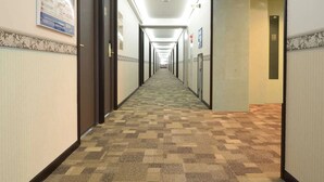 A hotel hallway with patterned carpet, doors on both sides, and a sign indicating the direction to the elevator. - Toyoko Inn Narita Airport Shinkan (Narita)