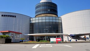 A modern building with a cylindrical central section and two large cylindrical wings. There is a sign with an arrow pointing to the right. - Toyoko Inn Narita Airport Shinkan (Narita)