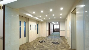 A hallway with tiled walls, a patterned carpet, and recessed ceiling lights. - Toyoko Inn Narita Airport Shinkan (Narita)