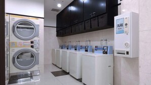 A laundry facility with multiple washing machines and dryers, a control panel, and a water dispenser. - Toyoko Inn Narita Airport Shinkan (Narita)