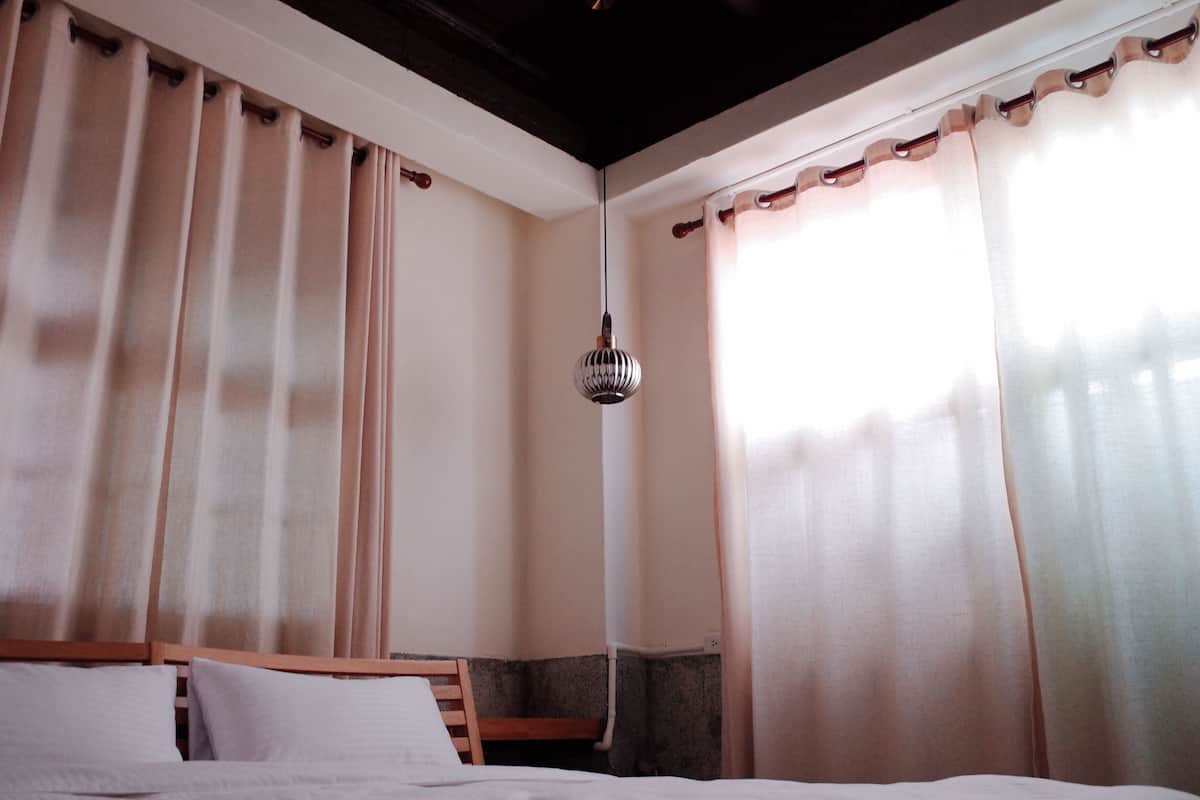 A bedroom with a bed, wooden headboard, and curtains.