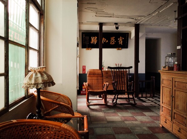 Una habitación tradicional con piso a cuadros, muebles de mimbre y un armario de madera.