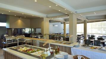 A buffet area with multiple serving stations, a variety of food options, and a seating area with tables and chairs.