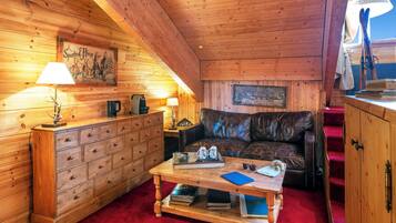 L’intérieur d’un chalet chaleureux, avec une commode en bois, un canapé en cuir et une table basse.