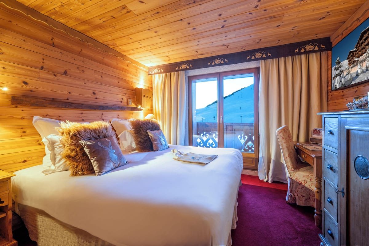 Une chambre de style cabane en bois, dotée d’un grand lit, d’un bureau et offrant une vue sur la montagne.