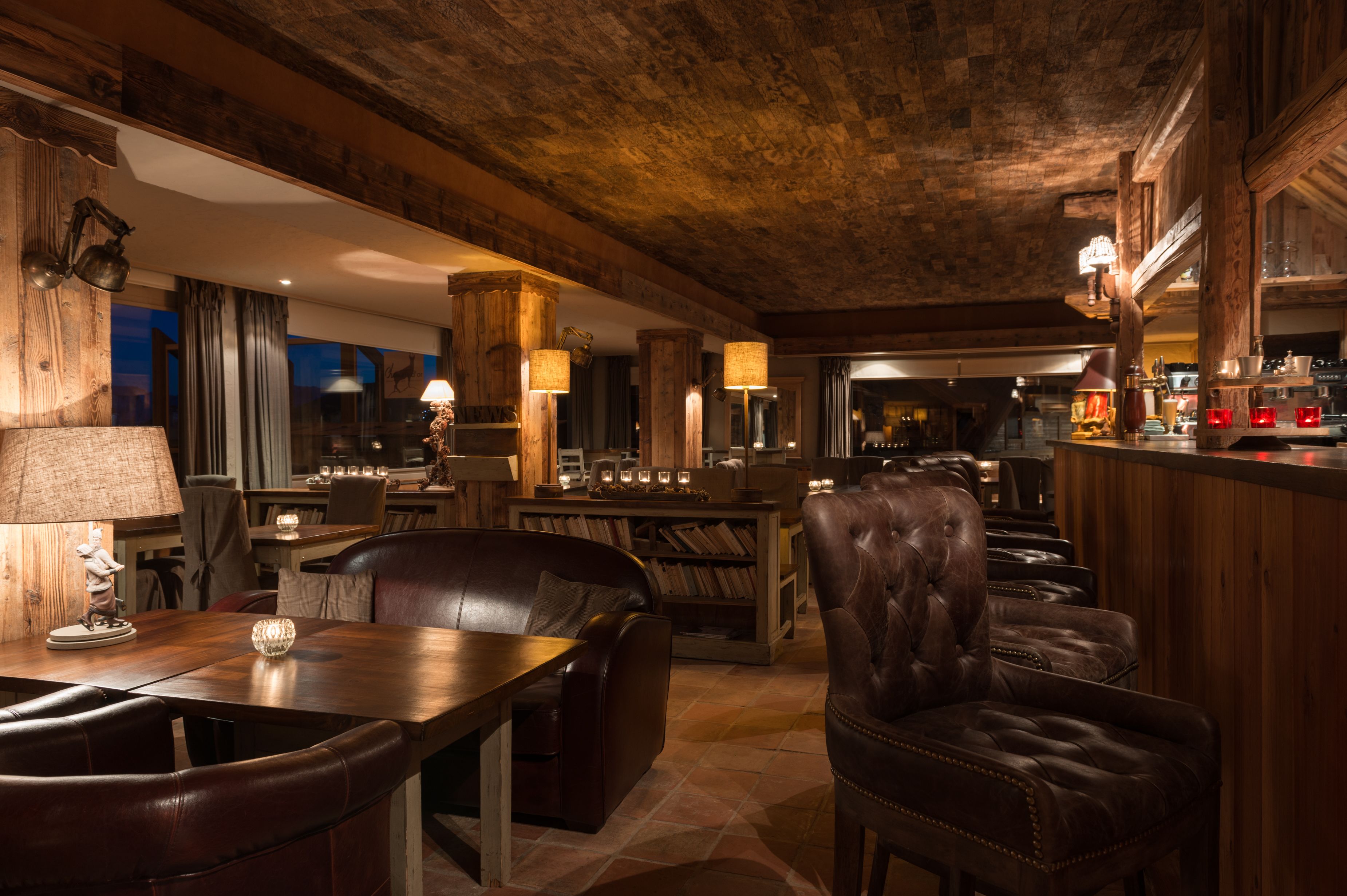 A cozy bar area with leather seating, wooden beams, and ambient lighting.