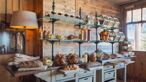 Un interior rústico de madera con una barra de desayuno repleta de pan, pasteles y bebidas.