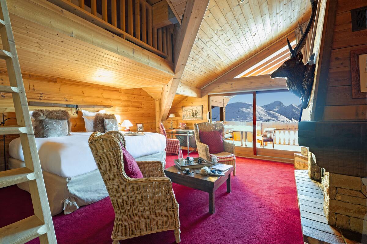 Une charmante cabane en bois avec un lit, des fauteuils en osier, une table basse et une vue sur les montagnes.
