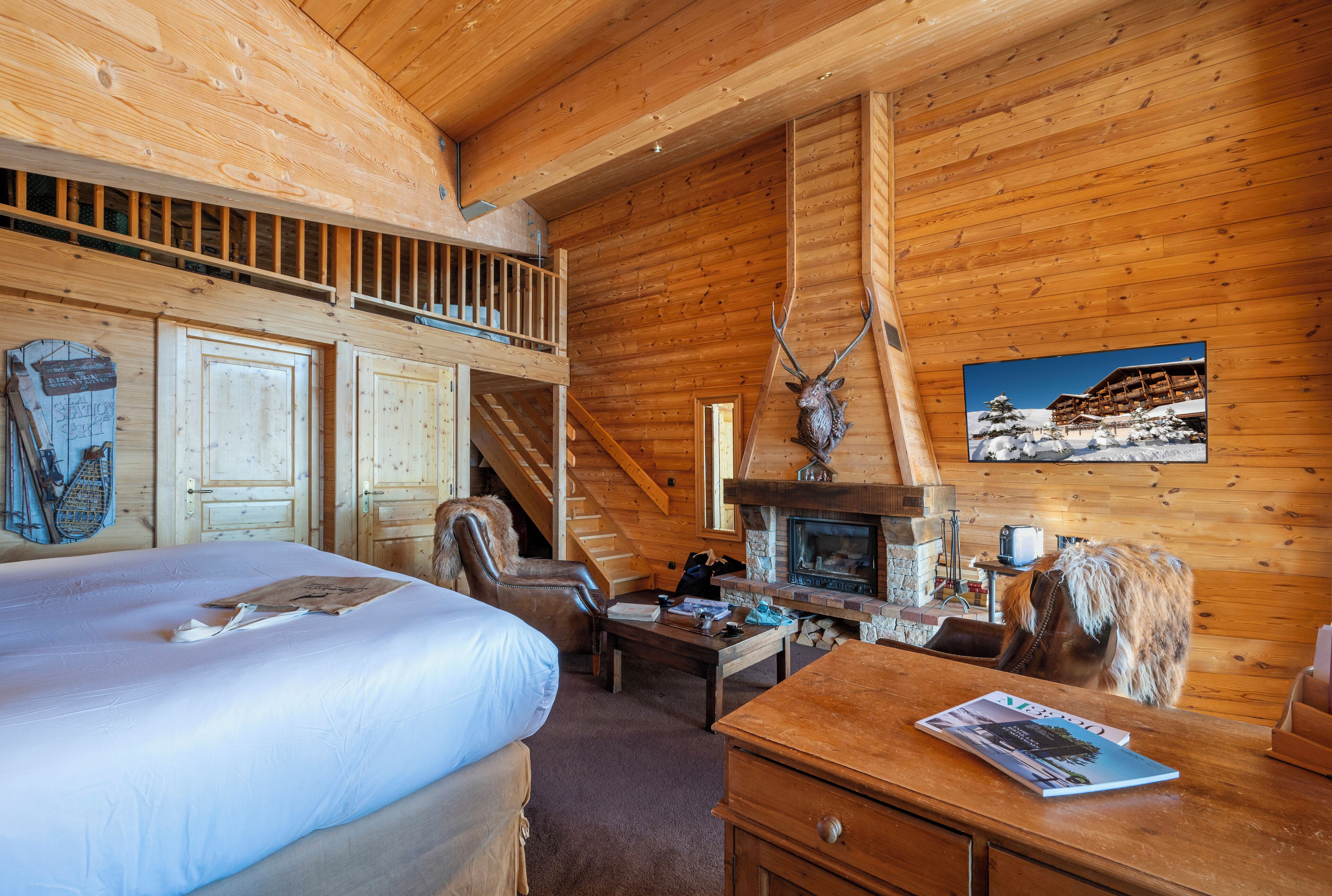 L’intérieur d’une cabane en rondins comprend un lit, une cheminée, une table à manger et un escalier menant à une mezzanine.