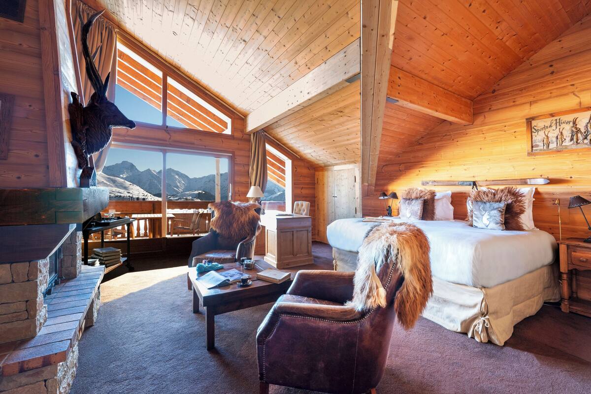 Une cabane en rondins avec un grand lit, une cheminée et une vue sur la montagne.