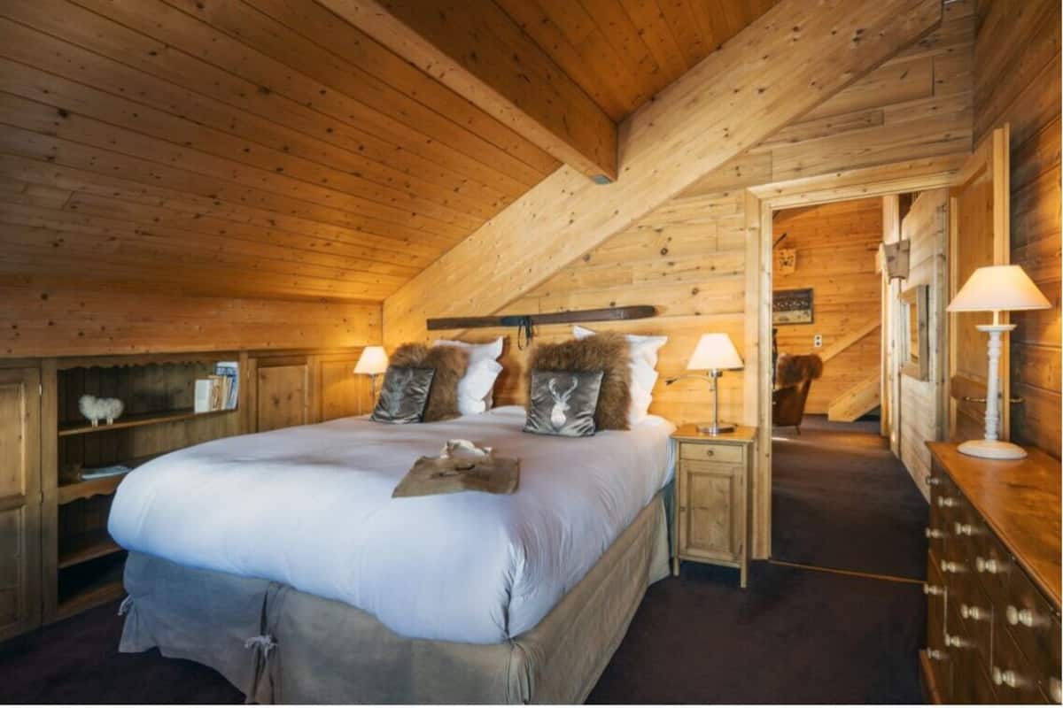Une pièce chaleureuse avec des murs en bois, un grand lit, deux tables de chevet avec des lampes et une armoire en bois.