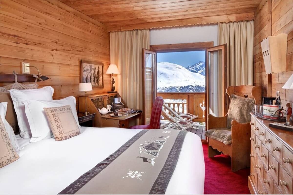 Une chambre confortable dans un chalet en bois, avec un lit, un bureau et une vue sur des montagnes enneigées.