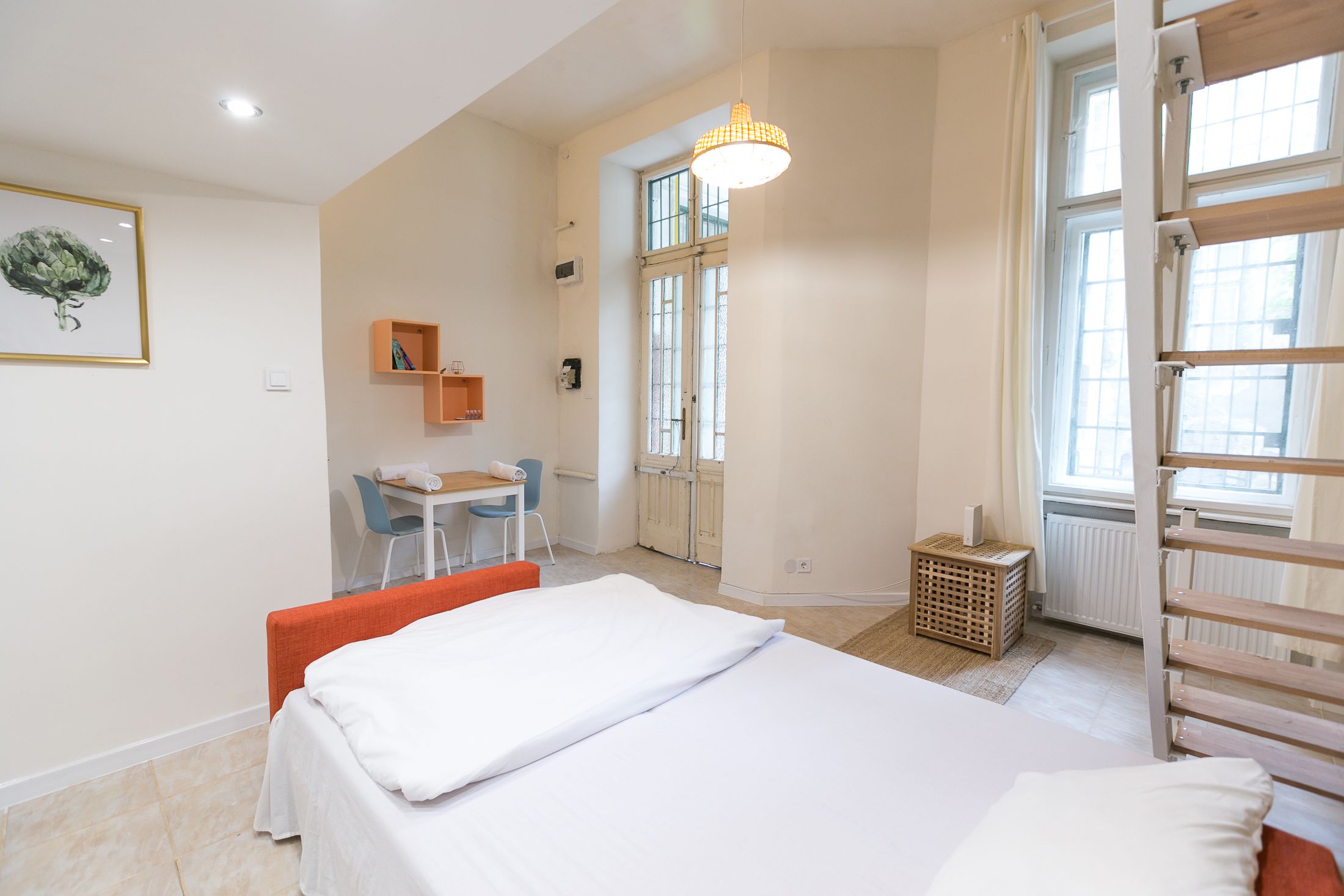 A bedroom with a bed, a desk, and a chair. There is a window with a view of the outside.