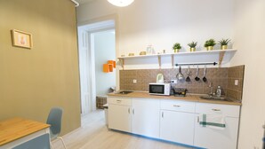 Cocina compacta con armarios blancos, microondas y pileta. Hay plantas en macetas sobre la encimera.