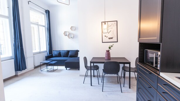 A modern living room with a sofa, a dining table with chairs, a TV, and a framed picture on the wall. - Modern Ernesto I (Budapest)