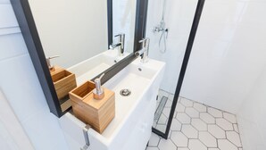A modern bathroom with a white bathtub, wooden storage boxes, a large mirror, and a shower area. - Modern Ernesto I (Budapest)